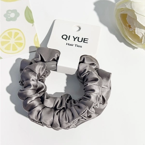 Détail d'un chouchou en satin gris foncé avec texture soyeuse sur une carte de présentation