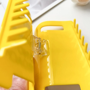 Detailed macro view of the yellow hair claw clip showing the metal spring and hinge
