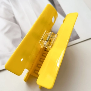 Macro view of bright yellow square hair claw clip with clear plastic spring mechanism
