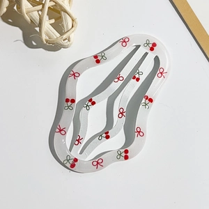 Dettaglio della clip per capelli bianco crema con motivi a ciliegia e fiocco rosso a onde