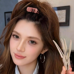 Pink root lifting clips and beige hair claw for volume styling on model's hair