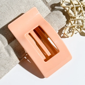 Detail view of 9.5cm matte peach pink shark hair claw clip on rustic fabric background