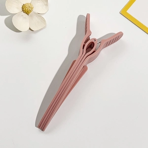 Detail of matte lotus root pink hair root clip with anti-slip design and metal spring