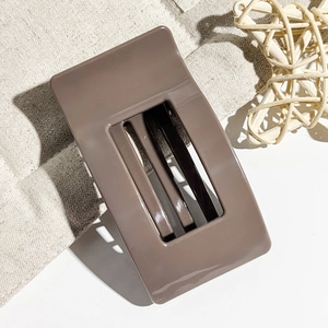 Detailed view of a brown rectangular hair claw clip with cutout design on linen fabric