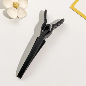 Close-up of black matte plastic crocodile hair clip with serrated teeth on white background