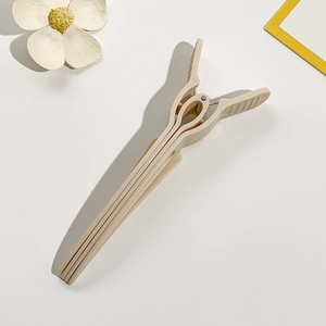 Detail of cream long-handle plastic hair clip with non-slip grip and metal spring