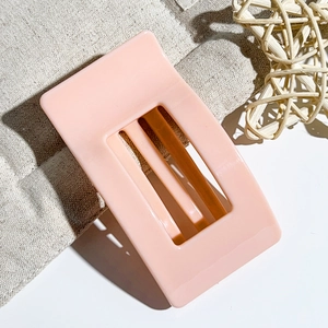 Detail of pink rectangular hollow hair claw clip on rustic beige fabric background