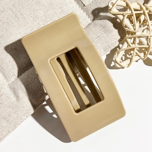 Close-up of a 9.5cm large khaki rectangular hair claw clip on textured beige fabric