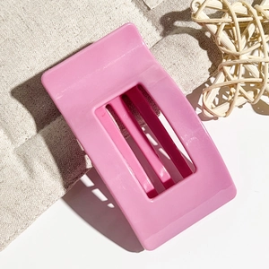 Detail view of a rectangle pink hair claw clip on a rustic beige linen background