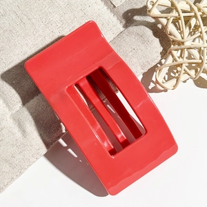 Close-up of a 9.5cm glossy red rectangular hair claw clip on a rustic linen background