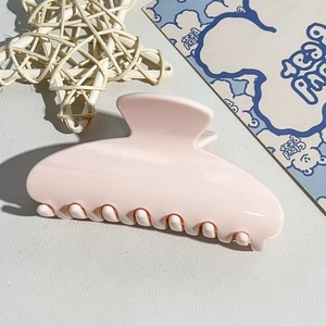 Detail of a large pale pink semi-circular hair claw clip with a glossy finish for women