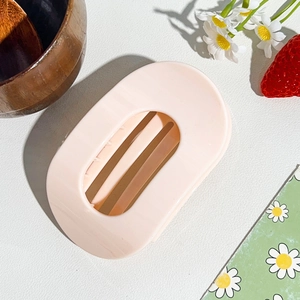 Detailed view of a light pink matte hollow hair claw clip on a minimalist wooden background