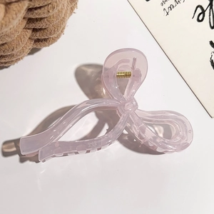 Détail d'une pince à cheveux rose translucide en forme de nœud avec ressort doré