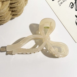 Détail d'une pince à cheveux en forme de nœud crème avec ressort en métal doré