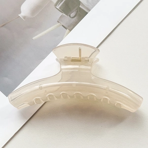 Détail d'une pince à cheveux nœud crème translucide avec ressort en métal doré robuste