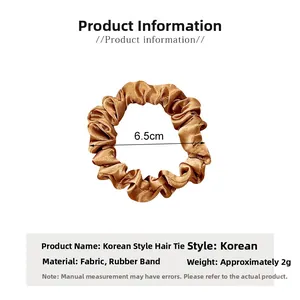 Detail shot of a brown satin pleated hair scrunchie showing 6.5cm diameter size