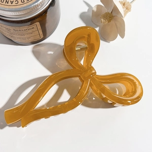 Detail view of large amber resin bow hair claw clip styled with decorative candles