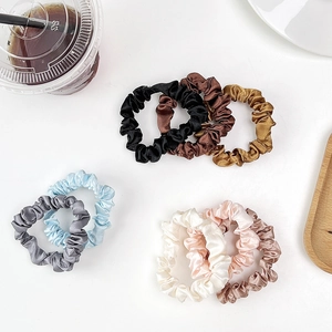 Detail of colorful silk satin scrunchies set displayed on minimalist white background