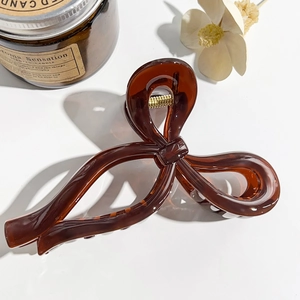 Close-up of a dark brown bow-shaped hair claw clip with amber resin texture