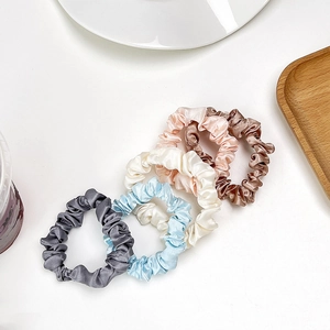 Detailed close-up of 5-pack pleated satin silk scrunchies in soft pastel color tones