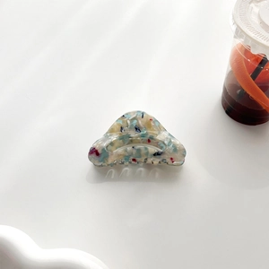 Détail d'une pince à cheveux en acétate avec motif marbré bleu et blanc sur fond blanc