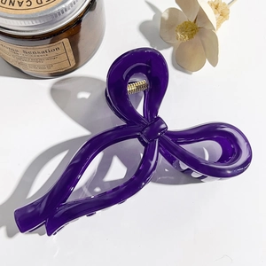 Detail view of a large deep purple bow hair claw clip with a glossy finish on white background