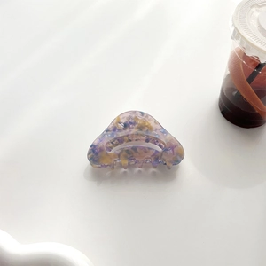 Détail d'une pince à cheveux élégante en acétate avec motif marbré violet et jaune artistique