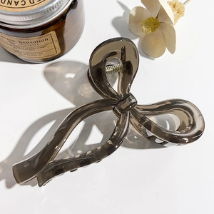 Detail of a brown bow hair claw clip made of acrylic on a white minimalist background
