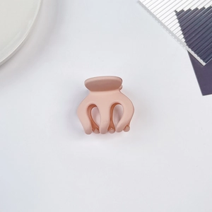 Gros plan sur une mini pince à cheveux rose mat avec design à trois dents sur fond blanc