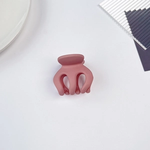 Pince à cheveux pieuvre rose poudré mat pour coiffage vue de dessus sur fond blanc