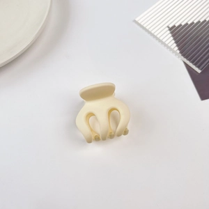 Gros plan d'une petite pince à cheveux crème sur une assiette minimaliste en céramique