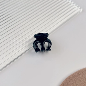 Gros plan d'une petite pince à cheveux noire brillante sur fond géométrique minimaliste