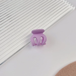 Gros plan sur une petite pince à cheveux violette mate avec un design à trois dents