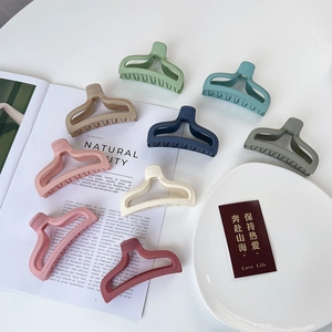 Close-up of matte fish-tail hair claws in nine colors arranged on a white tray