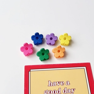 Détail de six petites pinces à cheveux en forme de fleurs mates aux couleurs pastel