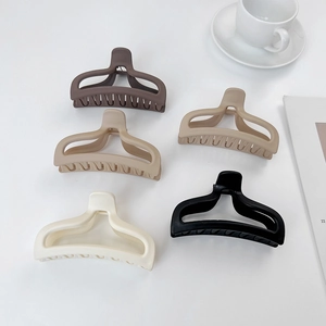 Top view of five matte large claw clips in neutral earth tones on a white minimalist background