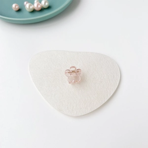 Gros plan d'une mini pince à cheveux fleur rose transparente sur fond décoratif doux
