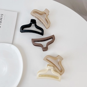 Flat lay of five matte mermaid tail hair claws in elegant neutral earth tones and cream