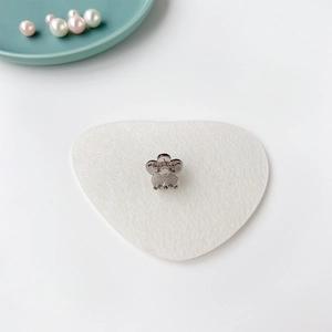 Vue détaillée de la mini pince à cheveux fleur gris fumé sur un coussin coeur