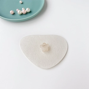 Détail d'une mini pince à cheveux fleur beige translucide sur un coussin blanc