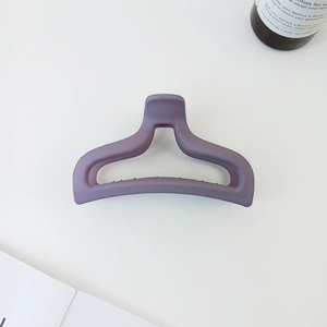 Close-up of a matte purple arched hair claw clip in a minimalist lifestyle setting
