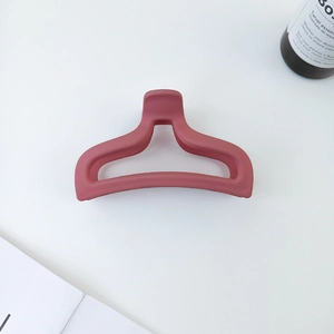 Close-up of matte dark pink hair claw clip with geometric hollow fishtail design