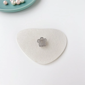 Détail d'une mini pince à cheveux fleur gris translucide sur fond de feutre blanc