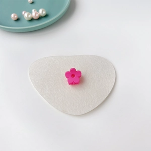 Détail d'une mini pince à cheveux fleur rose mat sur un tissu blanc en forme de cœur