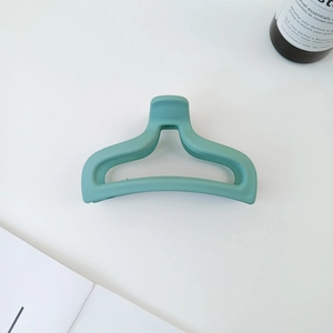 Detail view of a matte mint green hair claw clip with a hollow mermaid tail design