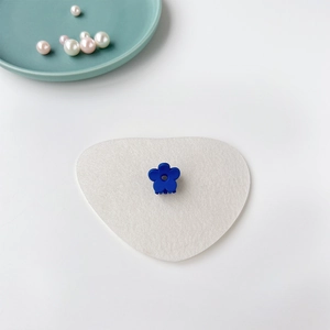Détail d'une mini pince à cheveux fleur bleu foncé sur un socle blanc en forme de cœur