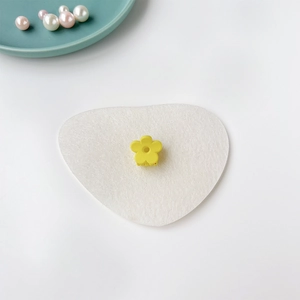 Gros plan d'une mini pince à cheveux fleur jaune mat sur une surface en feutre blanc