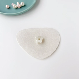 Détail d'une mini pince à cheveux en forme de fleur blanche sur un support décoratif