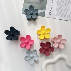 Flat lay of matte flower hair clips in seven colors with elegant magazine backdrop