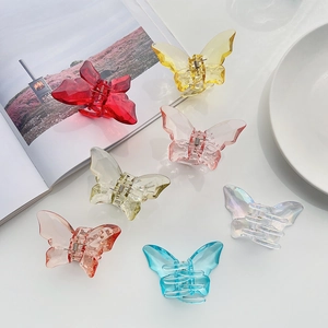 Close-up of translucent butterfly hair claws in various iridescent colors on white surface